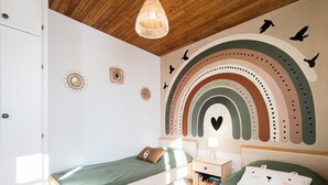 A child's bedroom with a bed, nightstand, and wall decorations including a rainbow and birds. - Gîtes de France® - La Belle Vue (SAINT PERDOUX)