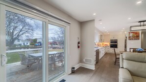 A modern kitchen with a large window, sliding glass door, and a view of the outdoors. - Bright Lakeside Cottage | 4br & 16 guest max | Private Dock & Nature Retreat (Georgina)