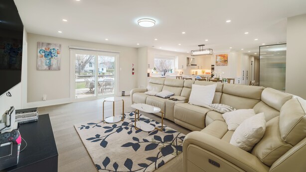 A spacious living room with a beige sofa, a coffee table, and a TV on a black stand. - Bright Lakeside Cottage | 4br & 16 guest max | Private Dock & Nature Retreat (Georgina)