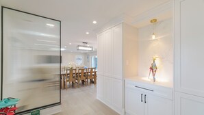A modern kitchen with white cabinetry, a dining area with wooden chairs, and a glass partition. - Bright Lakeside Cottage | 4br & 16 guest max | Private Dock & Nature Retreat (Georgina)