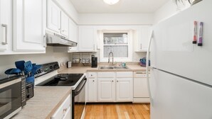 A modern kitchen with white cabinets, a stainless steel range, and a built-in dishwasher.