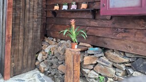 A rustic wooden cabin with a stone wall foundation, a wooden door, and a thatched roof. - Rose's Glamping (Rincón de la Victoria)