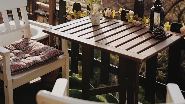 An outdoor wooden table with a vase of yellow flowers, a lantern, and a pine cone. - Rose's Glamping (Rincón de la Victoria)