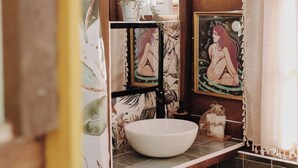 A rustic bathroom with a wooden ceiling, a large window, and a white sink. - Rose's Glamping (Rincón de la Victoria)