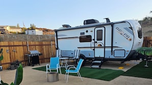 A recreational vehicle (RV) with a kitchen area, a grill, and a seating area with chairs.