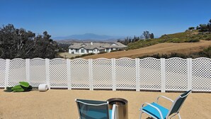 A patio with two chairs, a metal grill, and a white lattice fence.