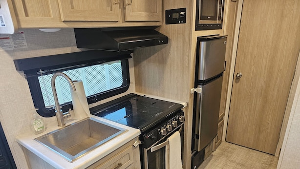 A compact kitchenette with a sink, stove, oven, microwave, and a small refrigerator.