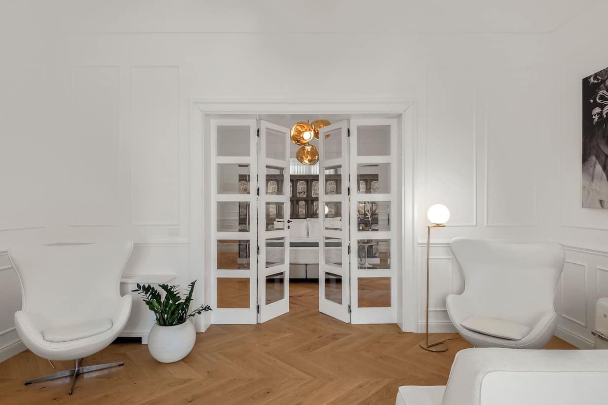A modern living room with white furniture, a potted plant, and a floor lamp.