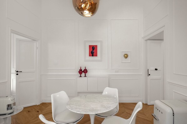 A modern kitchen with white cabinetry, a marble countertop, and a round table with four chairs.