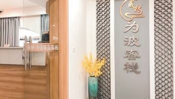 A reception area with a wooden reception desk, a wall-mounted sign with Chinese characters, and a decorative vase with yellow flowers.