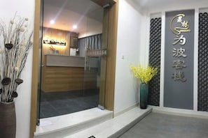 A reception area with a wooden reception desk, a glass door entrance, and a wall-mounted sign with Chinese characters.