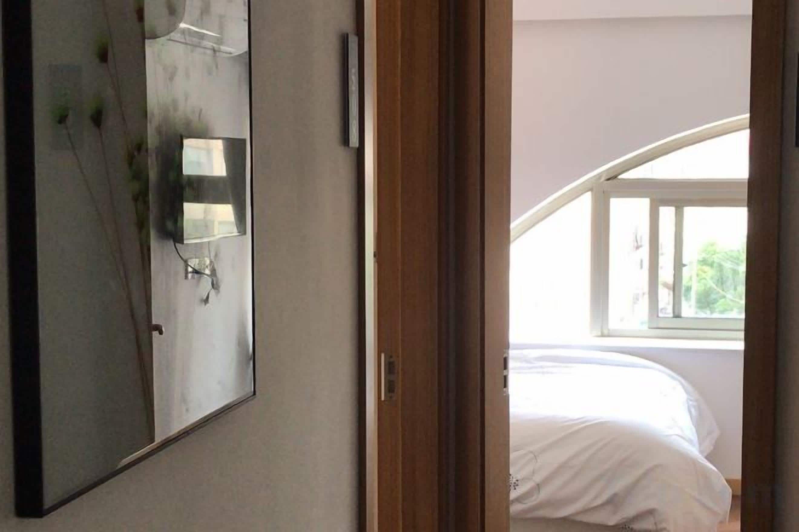 Une chambre à coucher avec un lit, un grand miroir et une fenêtre.