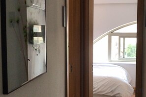 A bedroom with a bed, a large mirror, and a window.