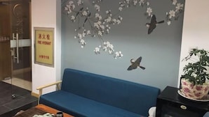 A room with a blue sofa, a wall-mounted floral decoration, and a sign indicating a fire hydrant location. - Weibo Inn (Shanghai Zhongshan Park) (Shanghai)