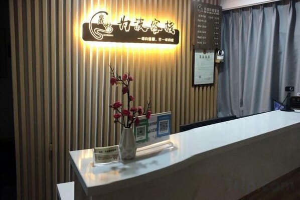 A reception desk with a sign above it, a vase with flowers, and a curtain to the right. - Weibo Inn (Shanghai Zhongshan Park) (Shanghai)