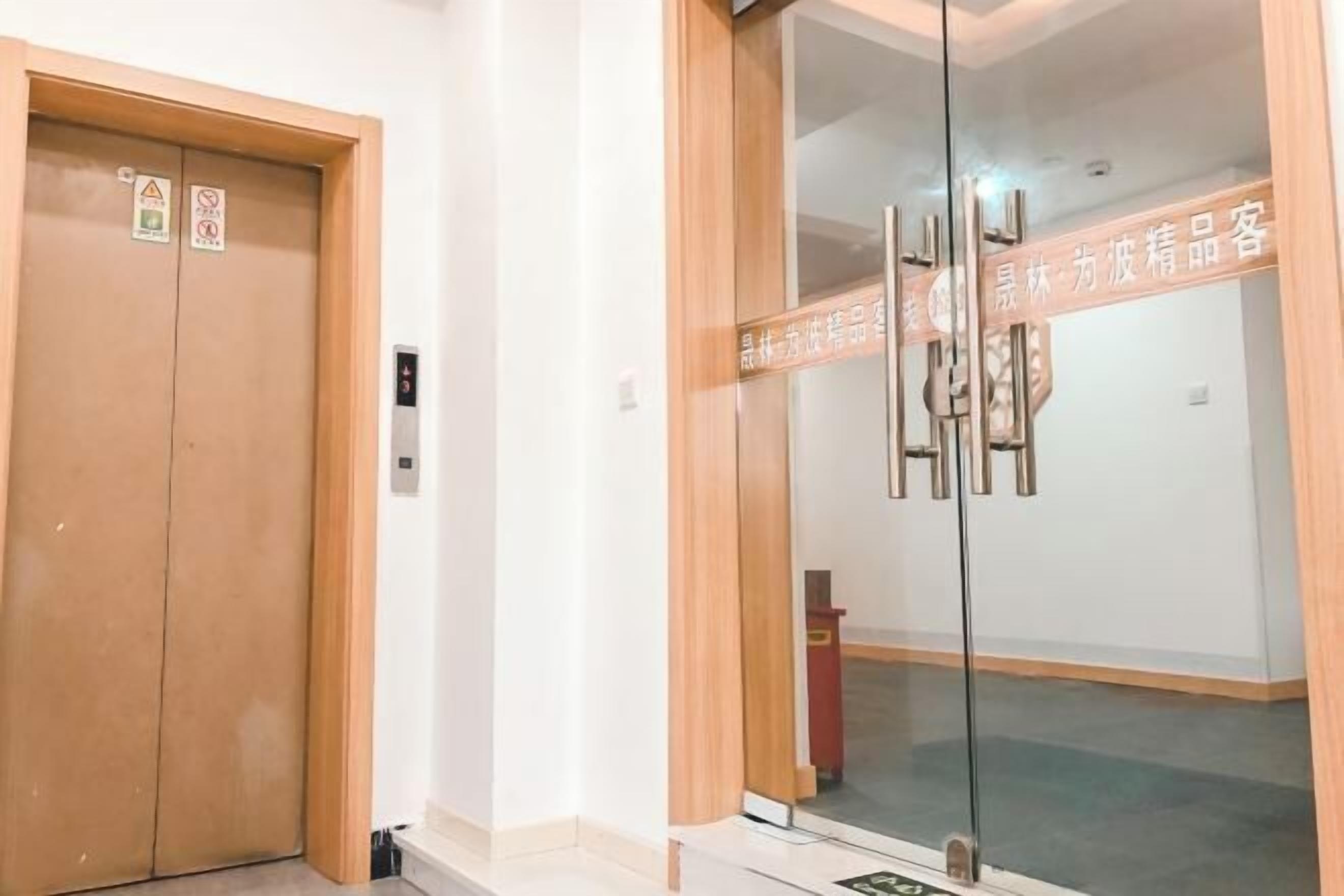 Entrada de hotel com porta de madeira e porta de vidro, com uma placa.