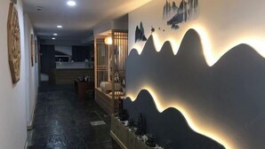 A hallway with a decorative wall featuring a mountain landscape and a small seating area with a table and chairs. - Weibo Inn (Shanghai Zhongshan Park) (Shanghai)