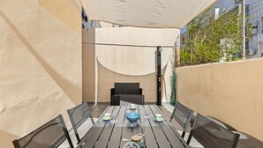 A small outdoor dining area with a table set for four, surrounded by chairs. - Alguerìta Apartment - Alghero (Alghero)