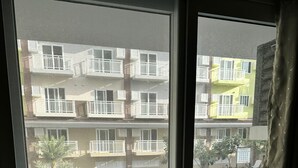 En utsikt från ett fönster mot en bostadsbyggnad med balkonger och en swimmingpool.