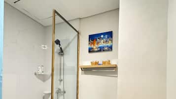 Un baño con cabina de ducha de vidrio, inodoro y lavamanos.