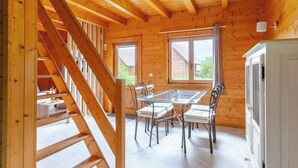 A wooden cabin interior with a dining table, chairs, and a staircase. - "Domaine la Clairière Le Douglas (Soultzmatt)