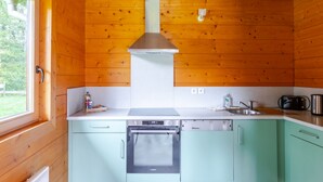 A compact kitchen with wooden walls, a stainless steel range hood, a built-in oven, and a sink. - "Domaine la Clairière Le Douglas (Soultzmatt)