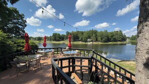 A wooden deck with outdoor seating and a view of a lake. - Scenic Stay | Indoor Pool, Rowboats & Relaxing Nature Views (Gladwin)