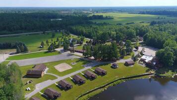 An aerial view of a campground with multiple cabins, a central building, and a lake.