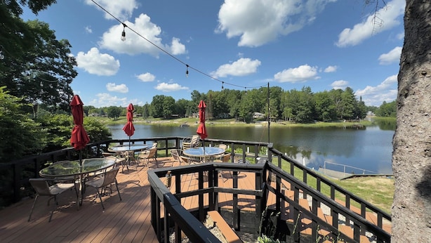 Una terraza de madera con mobiliario exterior y vista a un lago.