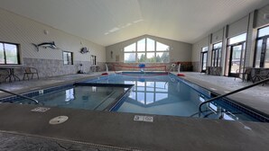Ein Hallenbad mit Sprungbrett, klaren Glaswänden und hoher Decke.
