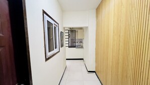 Un couloir étroit avec un mur lambrissé en bois, une porte dotée d’une poignée argentée et un tableau encadré accroché au mur.