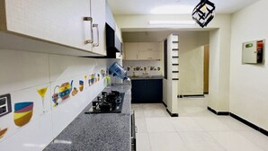 Une cuisine avec des armoires blanches, un comptoir en granit, une cuisinière à gaz et un luminaire suspendu.