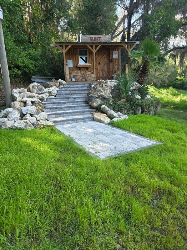 Un bâtiment en bois avec une enseigne indiquant « APPÂTS » et un escalier en pierre menant à l’entrée.