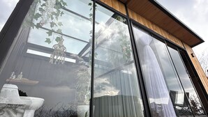 A modern building with large glass windows, wooden beams, and a view of a garden with a fountain. - Beautiful cabin/glamping in the city of Pereira, with beautiful view. (Pereira)