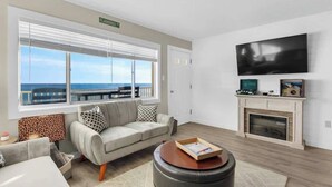 A living room with a sofa, a coffee table, a fireplace, and a TV mounted on the wall.