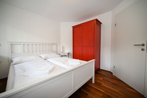 A bedroom with a white bed, a nightstand, and a red wardrobe. - Residence Alpin TOP 3 - Kaprun Incl Summer Card (Kaprun)