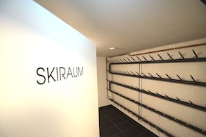 Una pared con la palabra "SKIRAUM" y un perchero con zapatos negros.
