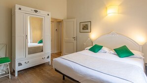 Ein Schlafzimmer mit einem Bett, einem Kleiderschrank, einer Tür und einer Wandleuchte.
