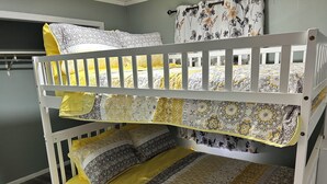 A bunk bed with two levels, each with a patterned bedspread and pillows. - Charming 2-bedroom cottage in welcoming Larned with AC,WiFi, full over full bunk (Larned)
