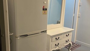 A compact kitchenette with a white refrigerator, a microwave, and a double door cabinet with a mirror. - 3 single and 2 sofa beds Studio Suite 7 (Auckland)