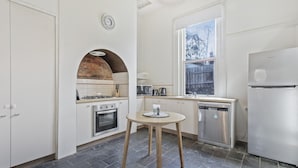 Una cocina con armarios blancos, un arco de ladrillo, un ventanal con vistas, una estufa, un fregadero y un lavavajillas.