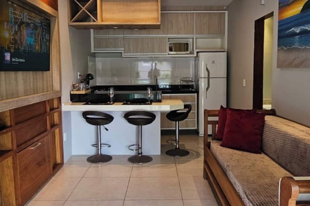 A modern kitchen with wooden cabinets, a ceiling fan, and a bar area with stools.