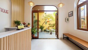 A reception area with a wooden reception desk, potted plants, and a bench. - The View Boutique Hoi An (Da Nang)