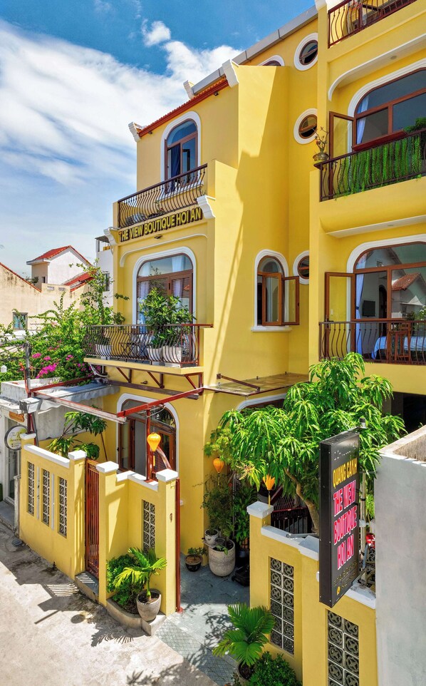 A yellow building with balconies and potted plants. - The View Boutique Hoi An (Da Nang)