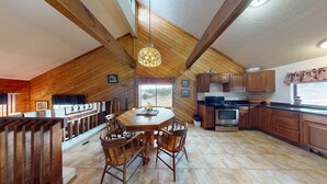 A spacious kitchen with wooden beams, a dining area with a large table and chairs, and a view of the outdoors. - Close to Lifts | Townhome | Angel View 2-3 (Angel Fire)
