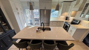 A modern kitchen with a large island, stainless steel appliances, and a view of the outdoors. - Charming Country Oasis (Alton)