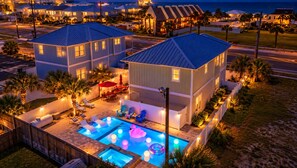 Propiedad residencial con piscina, mobiliario exterior y vista de la calle al anochecer.