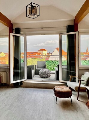 A spacious room with a large sliding glass door leading to an outdoor patio with wicker furniture and a decorative vase. - City-view Studio in Central (Dessau-Roßlau)