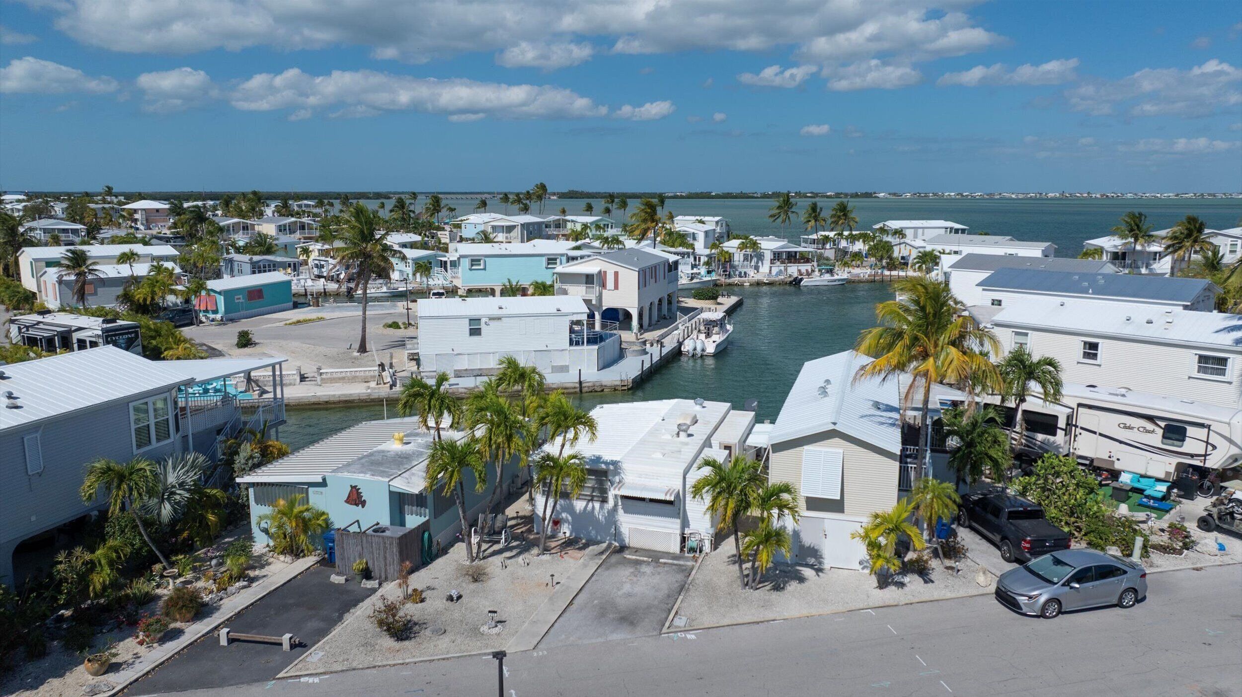 A marina with various boats docked, surrounded by residential buildings and palm trees.