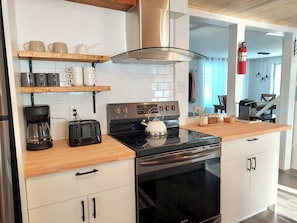 Uma cozinha moderna com armários brancos, fogão preto, cafeteira e torradeira.